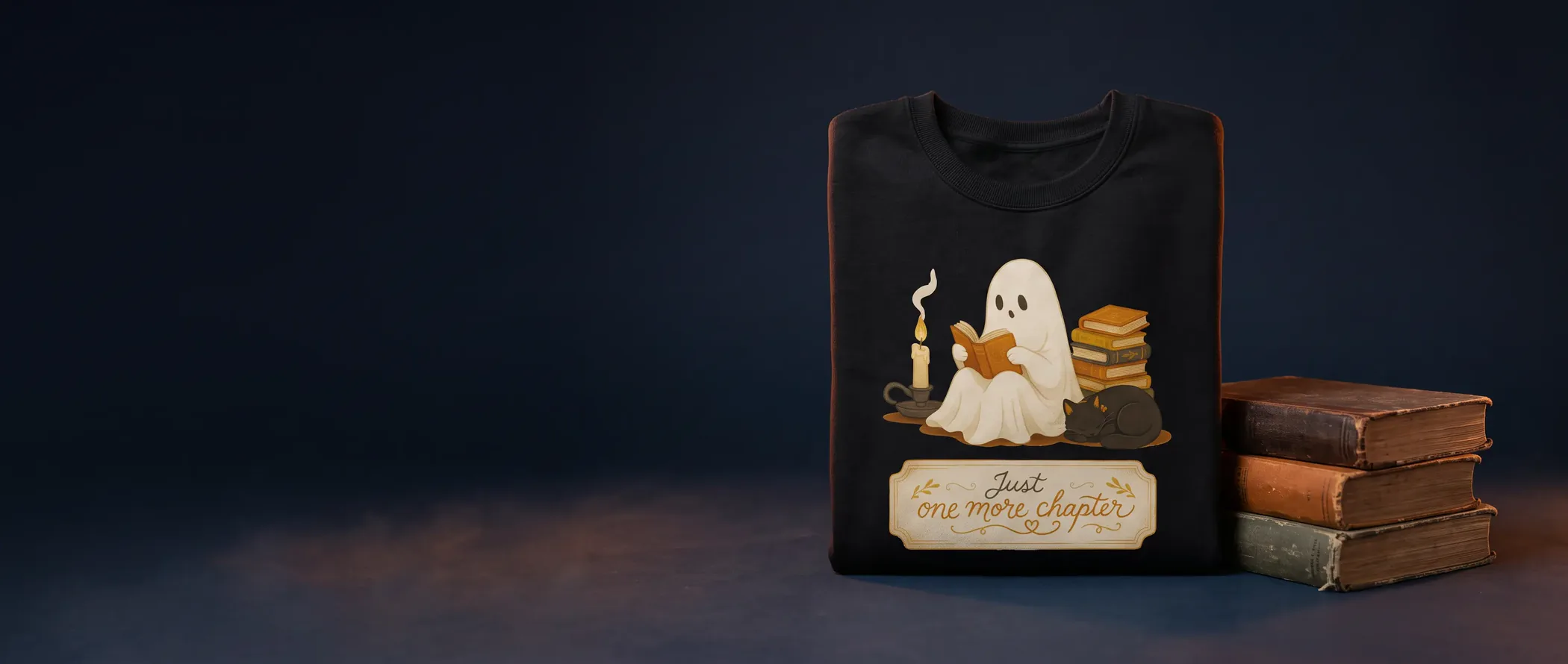 A sweatshirt reading 'Just one more chapter', with a little ghost reading by candlelight
